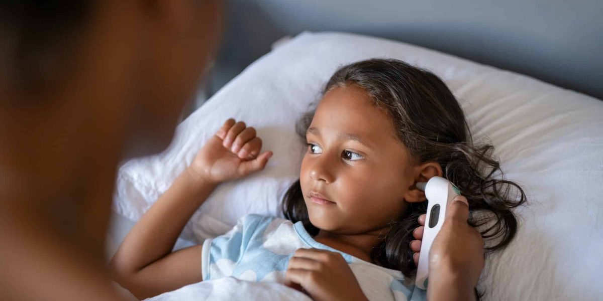 Mother checking daughter temperature with ear thermometer Mother checking daughter temperature with ear thermometer